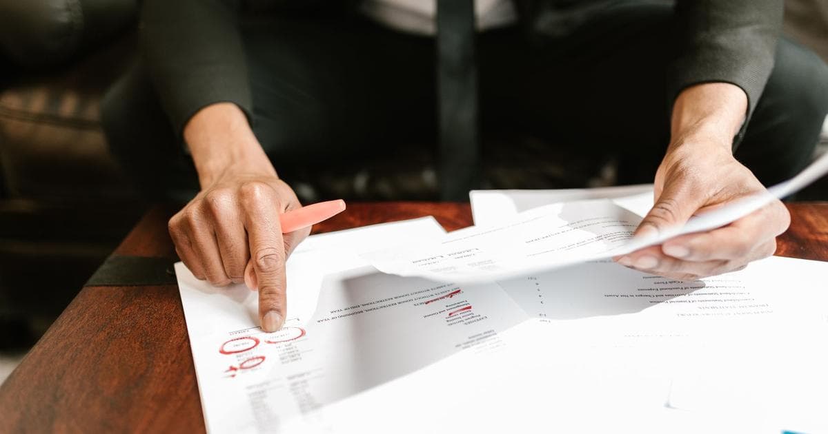 Close-up of a person reviewing invoice and tax paperwork at a desk, representing the documents a foreign-owned business gathers for Swedish VAT registration