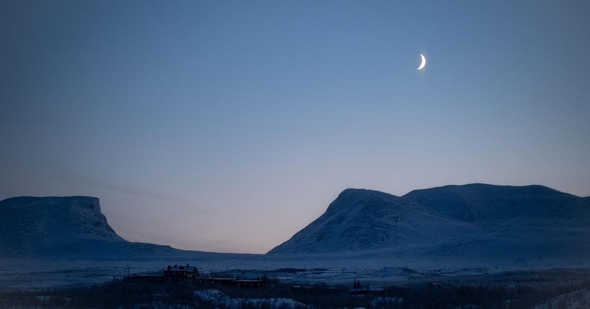 Dusk over the Abisko mountain valley, with the STF Abisko Turiststation buildings visible below.