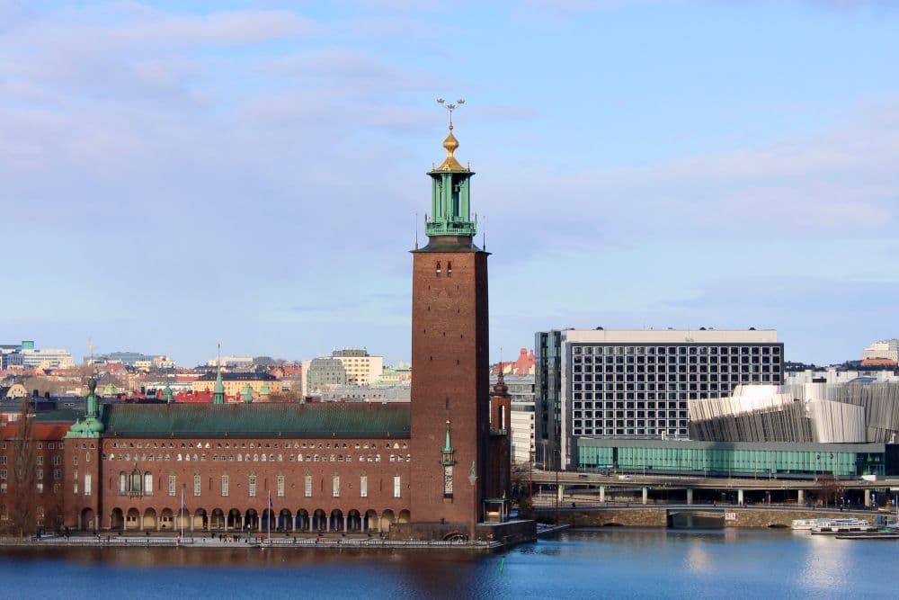 Stockholm City Hall viewed across the water on a clear day, representing the municipal and civic institutions that administer housing, registration and benefits decisions in Sweden