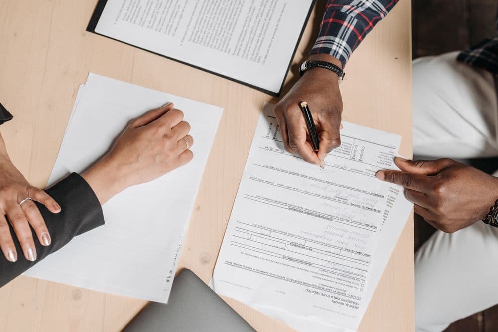 Two people signing paperwork at an office desk, representing the permit and residency applications foreign residents in Sweden have in progress